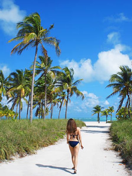 Miami Beach, United States - February 4, 2016: Tourist girl walk at the Crandon park Beach of Key Biscayne on sunny summer day in Miami.